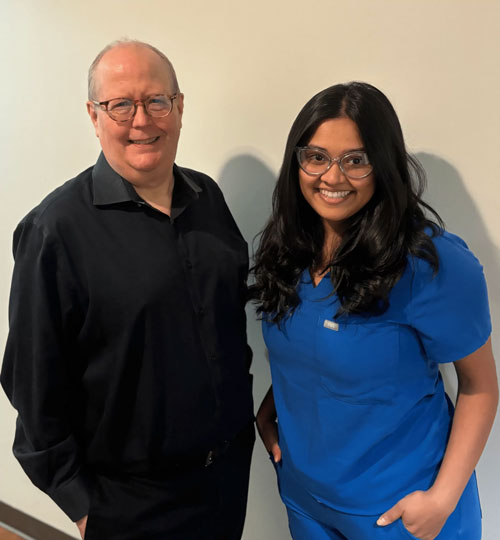 Two medical professionals, one in black shirt and one in blue scrubs